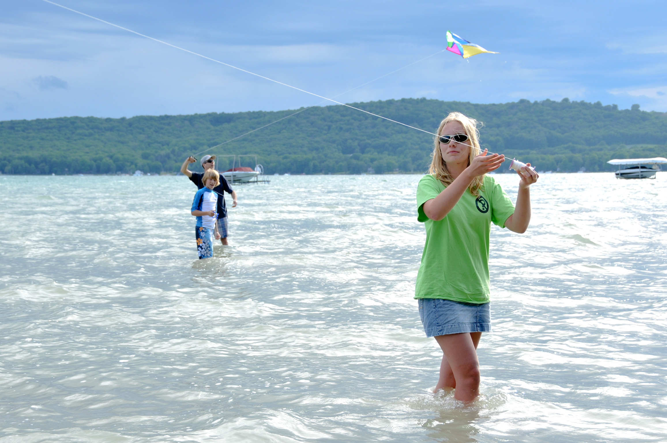 people wading in glen lake water with kites